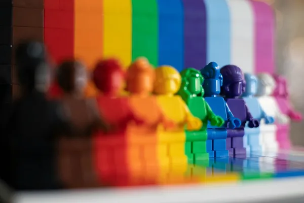 bunte Legofiguren, angeordnet im Farbverlauf der Progress-Pride-Flagge
