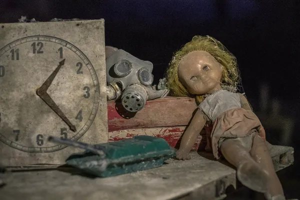 Postapokalyptisches Stillleben: verstaubte und kaputte Gegenstände, darunter Uhr, Puppe, ABC-Maske