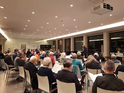 Quelle: Claudia Rauch Menschen sitzen in einen Saal mit Blick aus Fensterfront. Dort seht ein Fügel und ein Musiker