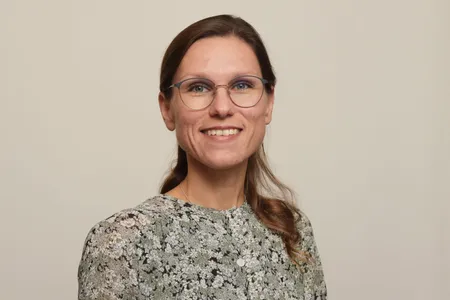 Portraitfoto der Theologin Dr. Antonia Lüdtke, eine junge Frau mit langen dunkelblonden Haaren und einer großen Brille