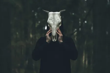 Mann verbirgt sein Gesicht hinter Tierschädel