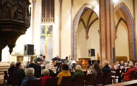 Publikum hört gespannt einen musikalischen Vortrag in einer alten Kirche