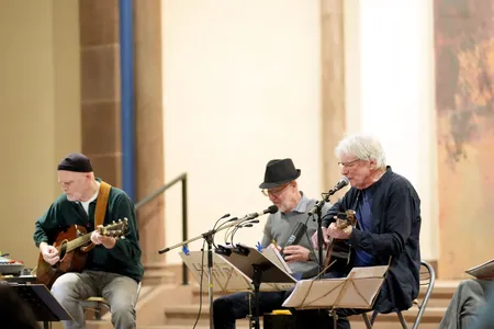 drei Musiker des Trios HinterSinn tragen ein Lied vor